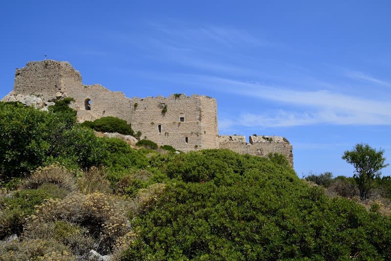 A serene historical site featuring ancient stone ruins amidst lush greenery under a clear blue sky, ideal for cultural exploration in Kritinia, Greece.