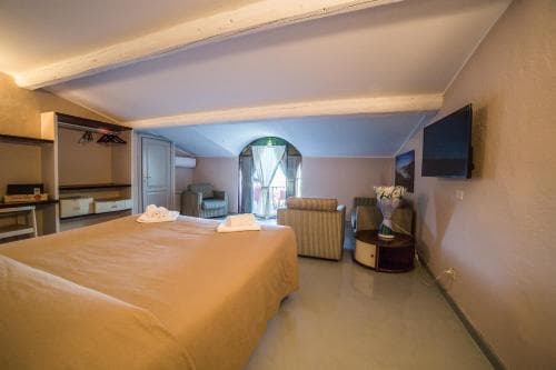 A cozy hotel room with a neatly made bed, arched window view, and modern amenities creates a serene atmosphere ideal for travelers seeking relaxation.