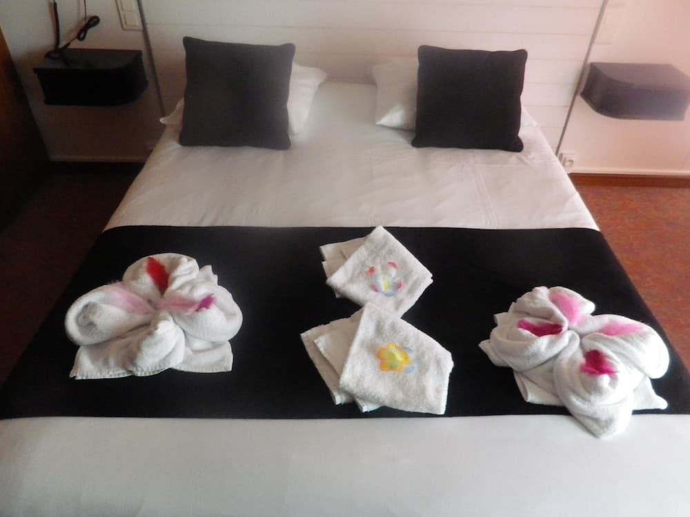 A cozy hotel room features a neatly made bed adorned with decorative towel flowers, creating a welcoming atmosphere ideal for travelers seeking comfort and relaxation.