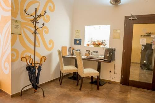 A cozy hotel lobby features a warm-toned interior with a decorative coat rack, comfortable seating by a desk adorned with flowers, and a welcoming atmosphere ideal for travelers seeking relaxation and convenience.