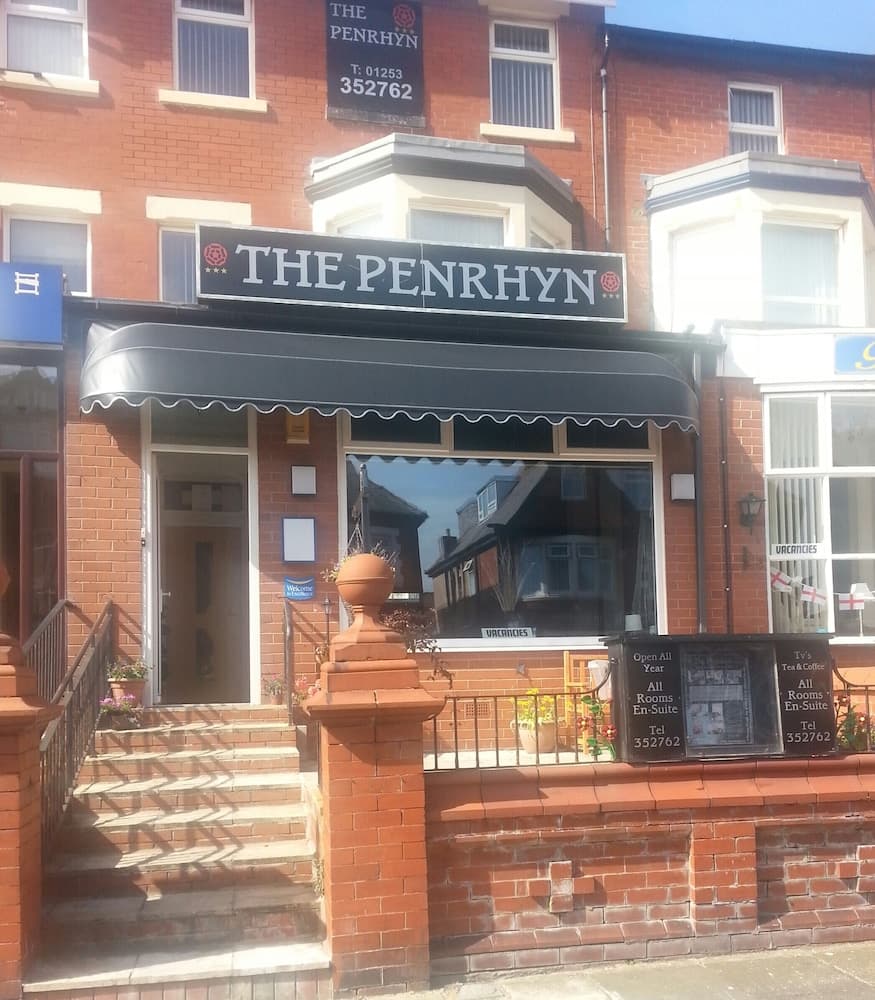 A charming brick building with "The Penrhyn" signage offers cozy accommodations with a welcoming entrance, ideal for travelers seeking a quaint stay in a picturesque urban setting.