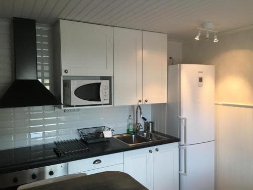A cozy, modern kitchen with white cabinets, stainless steel appliances, and warm lighting creates an inviting atmosphere ideal for travelers seeking a self-catering accommodation experience.
