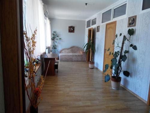 A cozy apartment hallway with wooden flooring, potted plants, and soft lighting creates a welcoming atmosphere, ideal for travelers seeking a comfortable and homey stay.