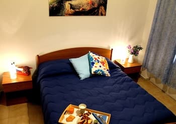 A cozy bedroom with a neatly made bed adorned with colorful pillows, warm lighting from bedside lamps, and a tray of breakfast items creates an inviting atmosphere ideal for a relaxing getaway.