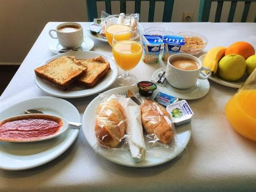 A cozy breakfast spread featuring toast, croissants, fresh fruit, coffee, and juice on a table in a hotel room, perfect for travelers seeking a refreshing start to their day.