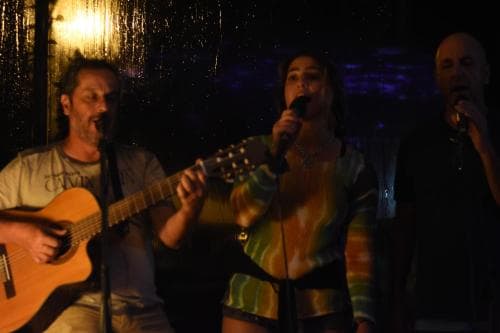 A cozy live music venue features performers illuminated by warm stage lights, creating an intimate atmosphere perfect for travelers seeking cultural experiences and nightlife entertainment.