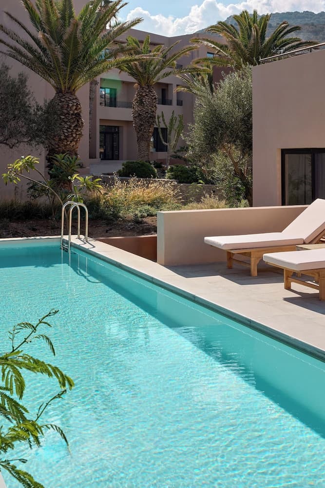 A serene tropical resort scene features a crystal-clear pool surrounded by lush palm trees and modern lounge chairs, ideal for relaxing vacations in a luxurious setting.