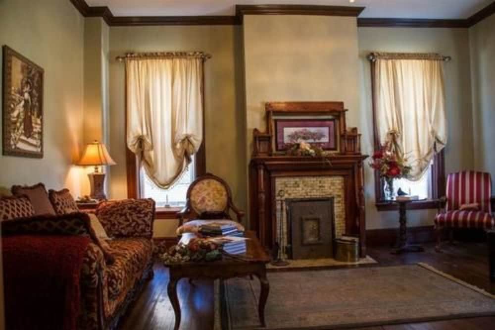 A cozy vintage living room with a fireplace, patterned furniture, and soft curtains creates an inviting atmosphere perfect for a heritage-themed getaway.