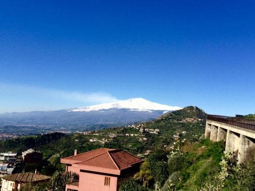 A serene landscape featuring a snow-capped mountain under a clear blue sky, with terraced hills, quaint houses, and a bridge, ideal for scenic photography and nature retreats.