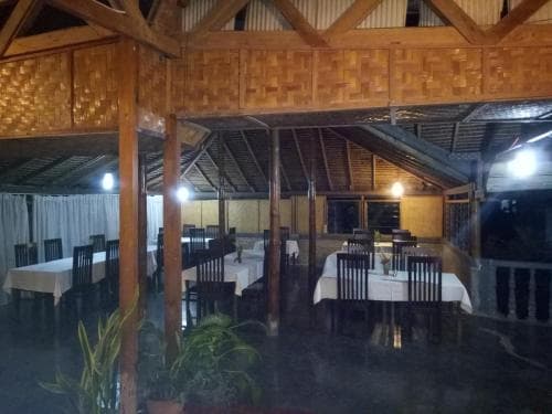 A cozy, rustic dining area with wooden beams and woven walls sets an intimate mood under warm lights, ideal for travelers seeking a unique cultural dining experience.