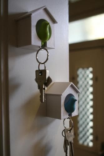 A charming indoor wall-mounted key holder designed as birdhouses with colorful birds perched on them, perfect for organizing keys in a cozy home setting, ideal for travelers seeking unique decor ideas.