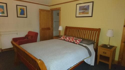 A cozy hotel room features a wooden bed with patterned pillows, framed artwork on the walls, and warm lighting, creating an inviting atmosphere ideal for travelers seeking comfort and relaxation.