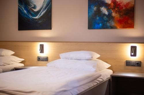 A cozy hotel room features neatly made beds under modern wall art, creating a serene atmosphere ideal for travelers seeking comfort and relaxation.