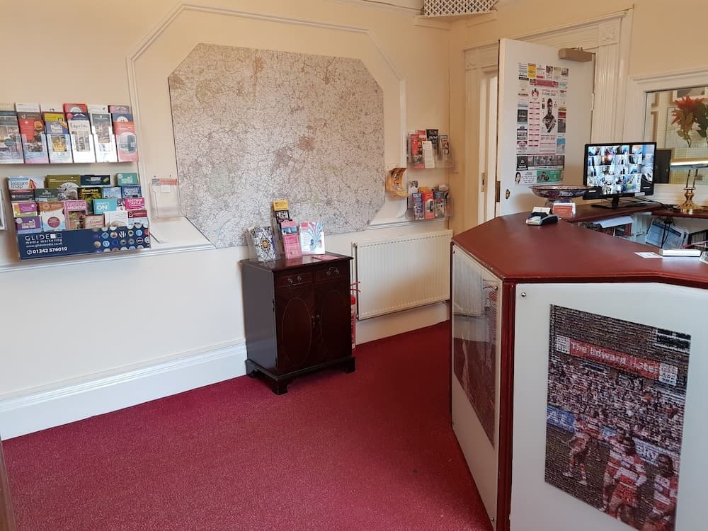 A cozy tourist information center features a vibrant red carpet, a wall-mounted map, brochures, and a reception desk adorned with a mosaic artwork, ideal for travelers seeking local attractions and services.