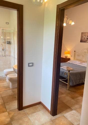A cozy hotel room with warm lighting, tiled floors, and an adjacent bathroom offers travelers a comfortable and inviting stay.