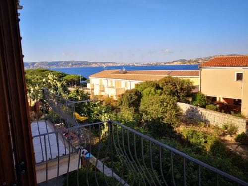 A serene balcony view overlooking lush greenery and a tranquil coastal landscape under a clear blue sky, ideal for a relaxing seaside getaway.