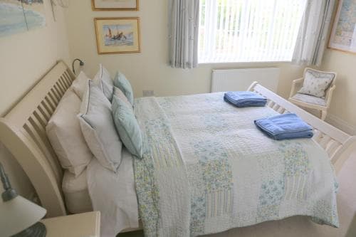 A cozy bedroom with a neatly made bed adorned in soft pastel linens, framed by natural light streaming through sheer curtains, evokes a serene and inviting atmosphere ideal for travelers seeking a tranquil retreat.