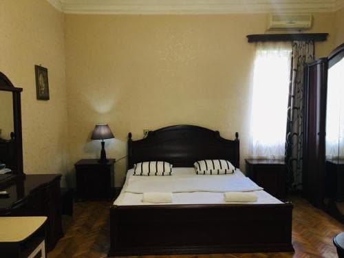 A cozy hotel room features a neatly made bed with striped pillows, wooden furniture, and soft lighting, creating a warm and inviting atmosphere ideal for travelers seeking comfort and relaxation.