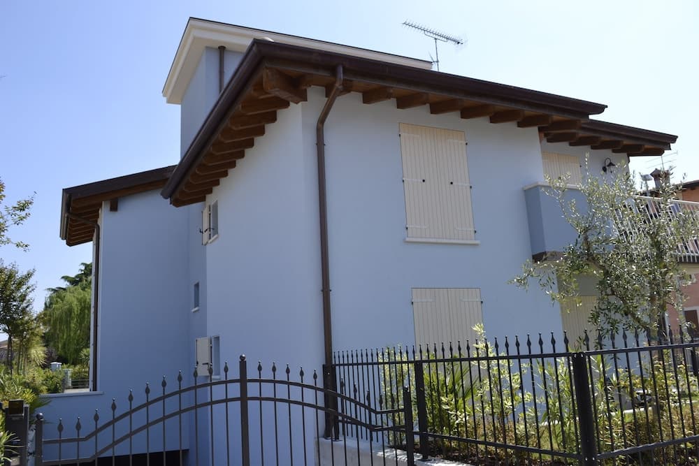 A serene suburban home with light blue walls, wooden accents, and a black wrought iron fence, ideal for family vacations in a quiet neighborhood.