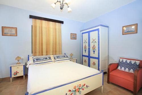 A cozy bedroom with light blue walls, floral-patterned furniture, and warm lighting creates a serene atmosphere, ideal for travelers seeking a peaceful retreat.