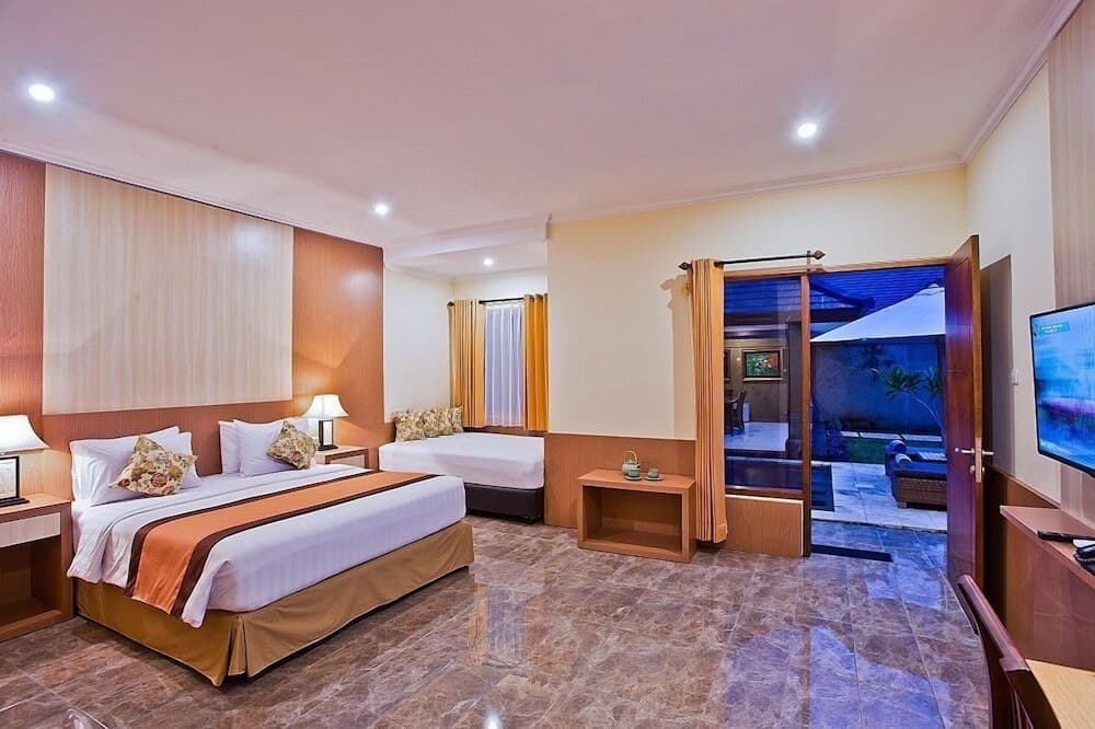 A cozy hotel room with warm lighting, wooden furnishings, and a private patio view offers travelers a comfortable retreat for relaxation and leisure.