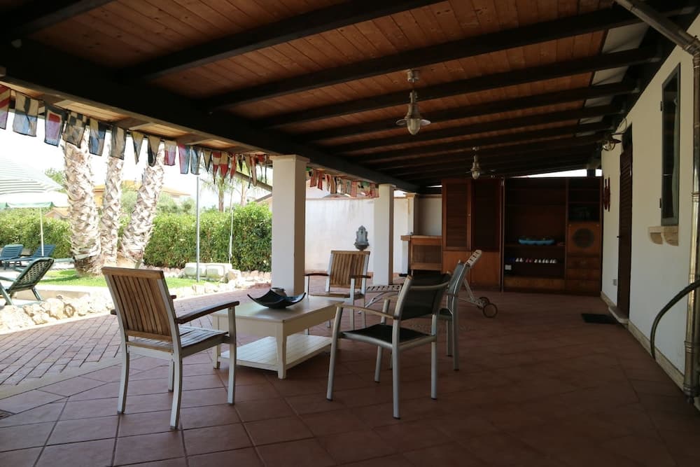 A cozy outdoor patio with wooden furniture, tiled flooring, and festive flags creates a relaxed atmosphere ideal for vacation rentals or family gatherings.