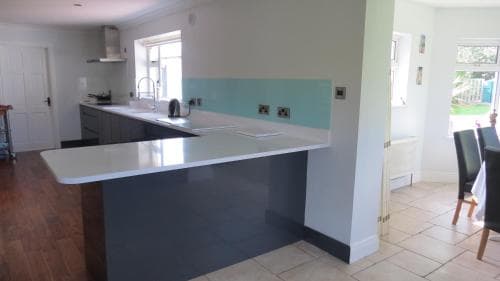 A modern kitchen with a sleek white countertop island, light blue accent wall, and tiled flooring creates a bright and inviting atmosphere, ideal for family gatherings or culinary enthusiasts exploring new recipes.