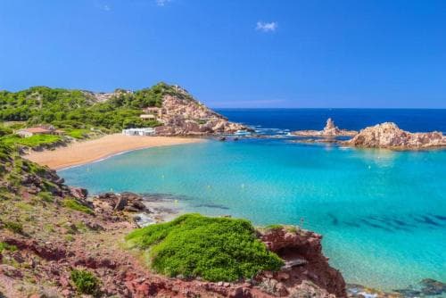 A serene coastal paradise features turquoise waters nestled between rugged cliffs and lush greenery, ideal for tranquil beach escapes and scenic photography.