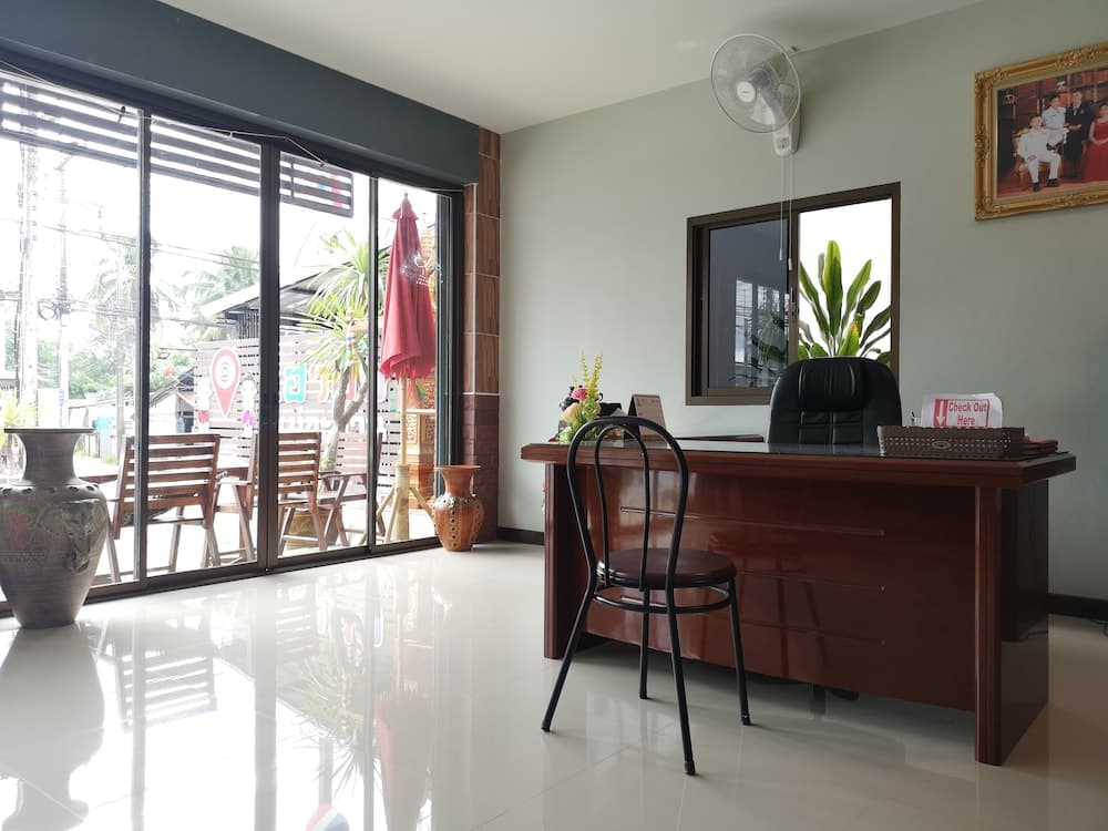 A serene hotel reception area features a polished desk, decorative vases, and a view of outdoor seating through glass doors, ideal for travelers seeking a calm check-in experience.