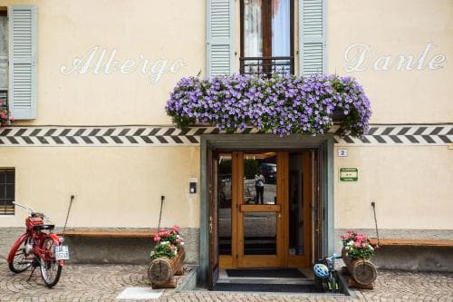 A charming European hotel entrance adorned with vibrant flower boxes and shutters, featuring bicycles parked outside, evokes a cozy and inviting atmosphere perfect for travelers seeking a quaint stay.