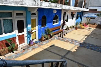 A vibrant courtyard with colorful tiled floors, potted plants, and charming blue and white houses creates a cozy, inviting atmosphere perfect for a relaxing getaway or cultural exploration.