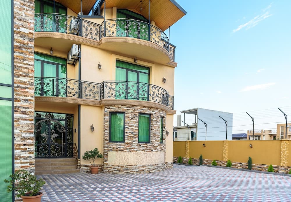 A charming multi-story villa with ornate balconies and a tiled courtyard exudes a serene and inviting atmosphere, perfect for a luxurious family vacation retreat.