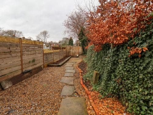 A serene autumn garden path lined with gravel and stone slabs winds through vibrant orange foliage and lush greenery, ideal for a peaceful stroll or photography session.