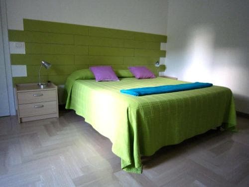 A cozy hotel room features a vibrant green bedspread and matching wall paneling, creating a cheerful and inviting atmosphere ideal for travelers seeking comfort and relaxation.