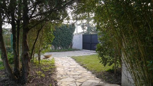 A serene garden pathway lined with lush greenery leads to a tranquil courtyard, ideal for a peaceful retreat or a nature-inspired vacation spot.