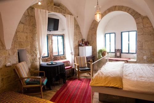 A cozy, rustic bedroom with stone walls, arched windows, and warm lighting creates an inviting atmosphere, perfect for travelers seeking a charming and intimate accommodation experience.