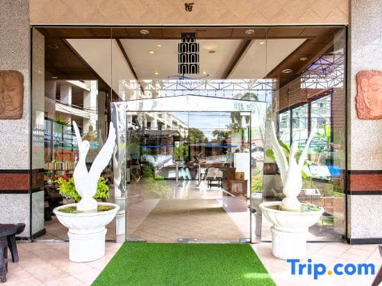 A welcoming hotel entrance features glass doors, vibrant greenery, and cultural sculptures, creating an inviting atmosphere ideal for travelers seeking comfort and local charm.