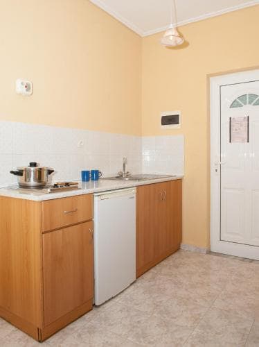 A cozy kitchenette with wooden cabinets, a white dishwasher, and tiled walls offers a practical space for travelers seeking self-catering accommodations in a warm and inviting setting.