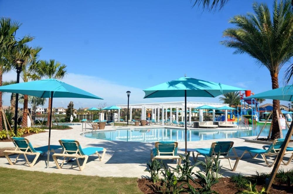 A serene resort poolside scene features turquoise umbrellas and lounge chairs under palm trees, ideal for relaxing vacations in sunny destinations.