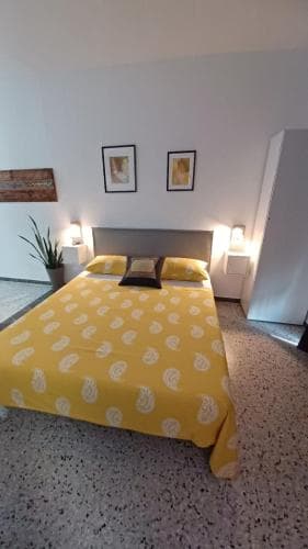 A cozy bedroom with a vibrant yellow patterned bedspread, minimalist decor, and soft lighting creates a serene atmosphere ideal for travelers seeking relaxation and comfort.