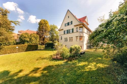 A serene suburban villa with a well-manicured lawn and lush greenery under a bright blue sky, ideal for a peaceful family getaway or a tranquil vacation rental experience.