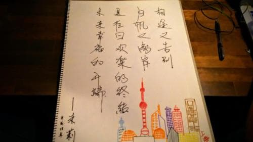 A notebook page features vibrant drawings of iconic city skyscrapers alongside elegant Chinese calligraphy, set on a wooden desk, evoking a creative and reflective mood ideal for travelers seeking cultural inspiration.