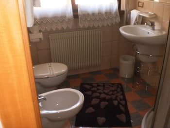 A cozy bathroom with checkered tiles, a heart-patterned rug, and soft natural light filtering through lace curtains, ideal for travelers seeking a quaint and inviting accommodation.