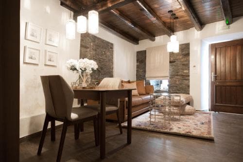 A cozy living room with rustic wooden beams, stone walls, and warm lighting creates an inviting atmosphere, perfect for travelers seeking a charming and comfortable retreat.