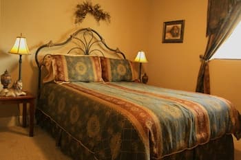 A cozy bedroom with warm lighting, patterned bedding, and elegant furnishings creates an inviting atmosphere, perfect for travelers seeking comfort and relaxation during their stay.