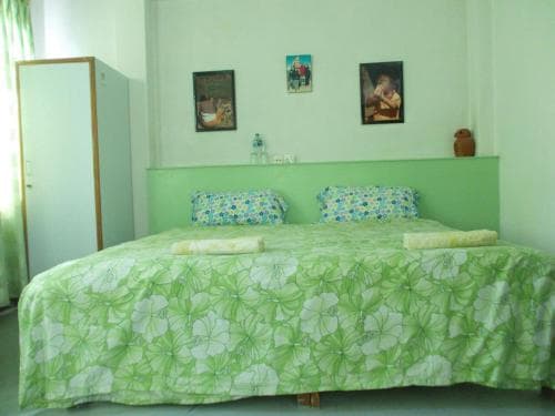 A cozy bedroom with green floral bedding, framed artwork on the walls, and soft lighting creates a serene atmosphere ideal for travelers seeking a peaceful retreat.