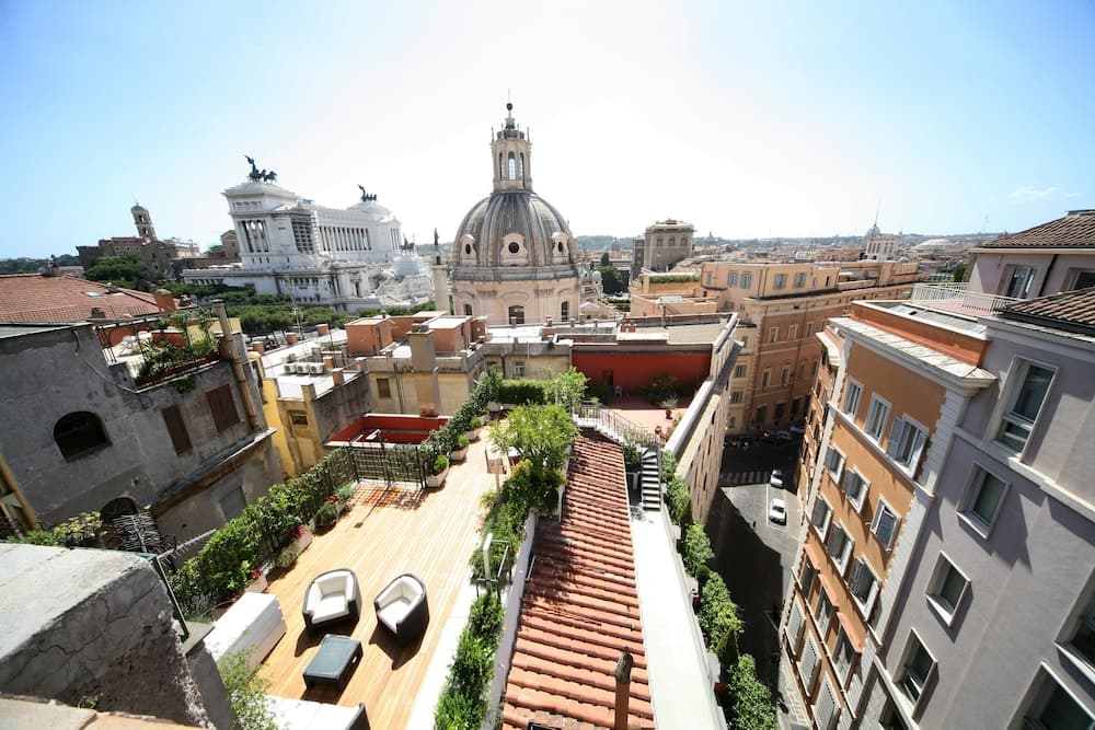 A serene rooftop terrace adorned with modern seating overlooks the historic cityscape featuring iconic domes and architecture, ideal for travelers seeking a tranquil urban retreat.