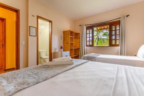 A cozy hotel room with neatly made beds, wooden furniture, and a window offering a serene view of palm trees, ideal for travelers seeking relaxation in a tropical setting.