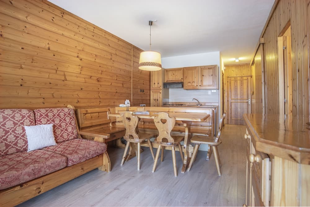 A cozy wooden cabin interior featuring a rustic dining area, patterned sofa, and kitchenette, ideal for a serene mountain retreat or vacation rental.