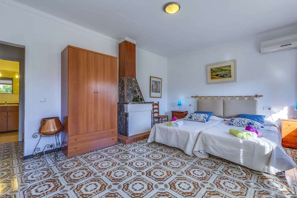 A cozy bedroom with patterned tile flooring, wooden furniture, and soft lighting creates a serene atmosphere ideal for travelers seeking relaxation in a vacation rental.